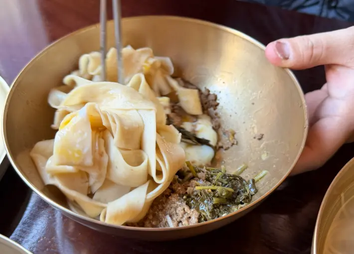 Mixing handmade noodles with sauce at Myeon Seoul